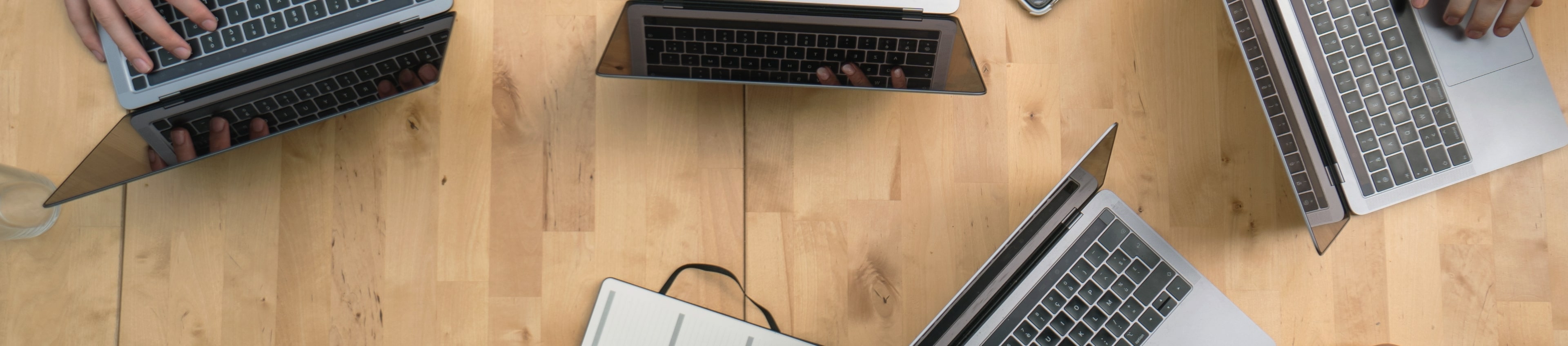 Image features a wood table with laptops on it.
