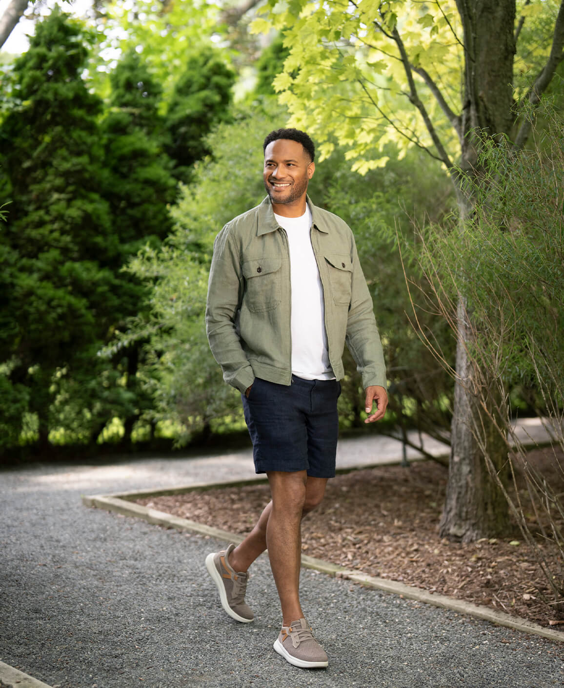 Image features a man walking on a gravel path in Florsheim sneakers.
