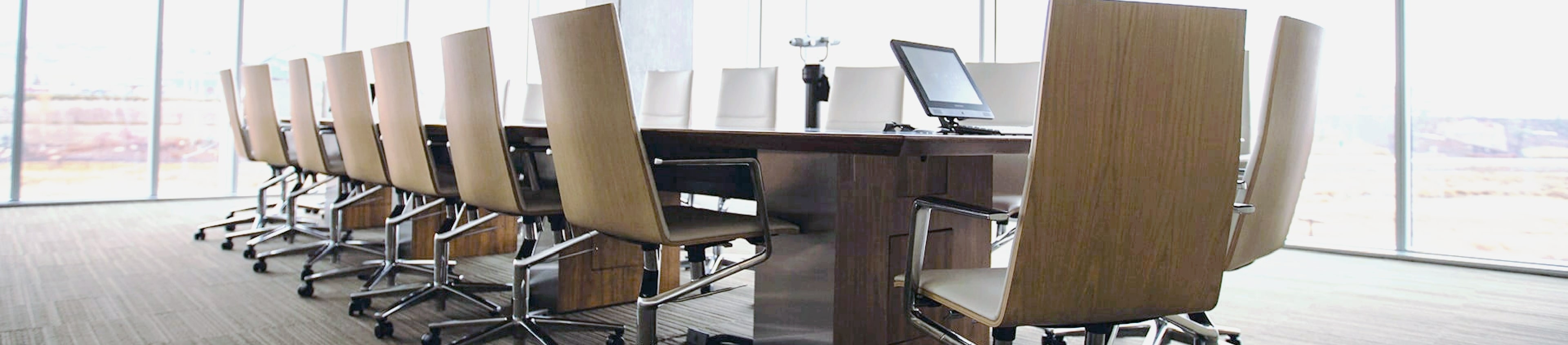 Image features a boardroom with a long table with chairs.