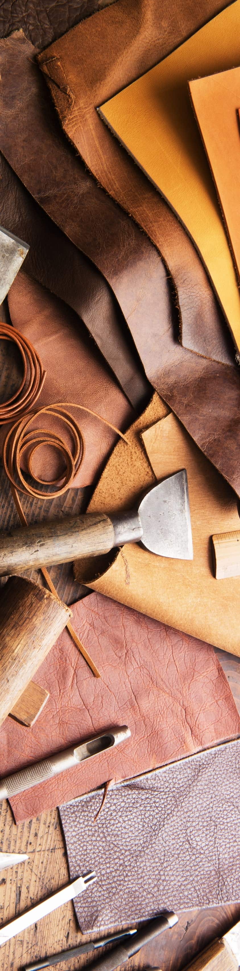 The image is an above shot of various leather materials and tools for leathermaking.